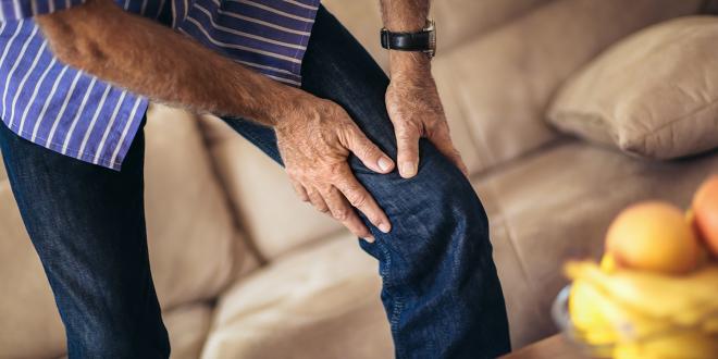 a middle-aged man grabbing his bad knee in pain