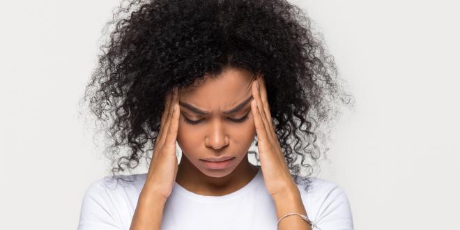 a woman with a serious headache rubbing her temples