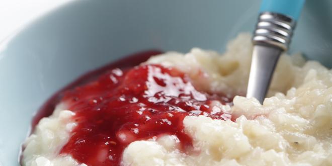 a bowl of rice pudding drizzled with a berry sauce