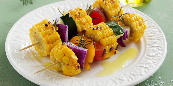 a plate of grilled vegetables on skewers with oil and seasoning