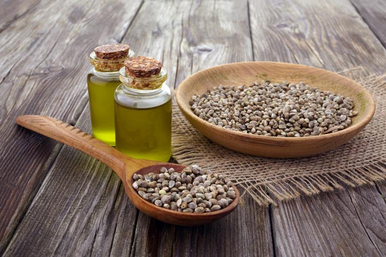 a bowl of hemp seeds and vials of oil